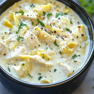 Bowl of creamy white chicken lasagna soup with shredded chicken, lasagna noodles, herbs, and black pepper.